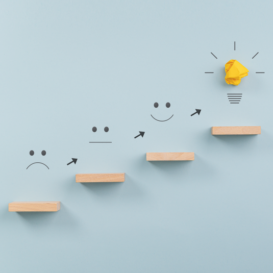 Symbolische Darstellung von Widerstand bis Flow (Holztreppe mit Smileys und Glühbirne am Ende)