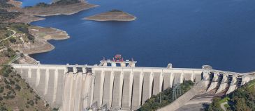 Wasserkraft: Kraftwerk mit Damm und Stausee im Hintergrund.