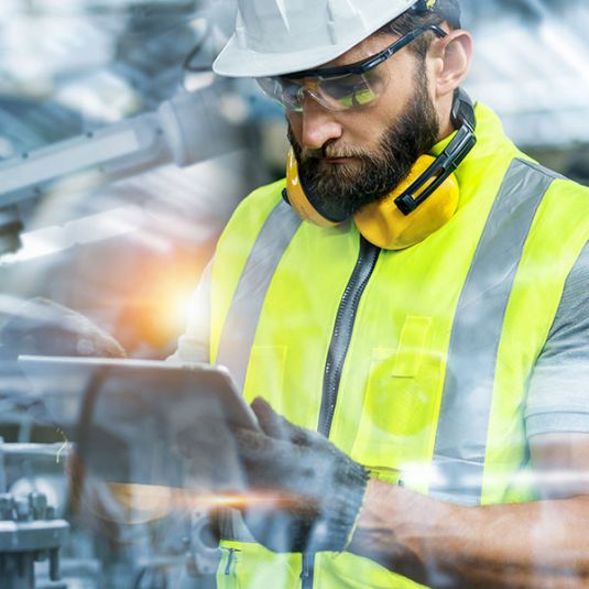 Industrial plant construction: Worker uses tablet in industrial plant.