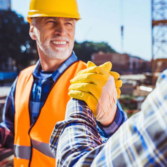 Industrial plant construction: Two workers on the construction site shaking hands.