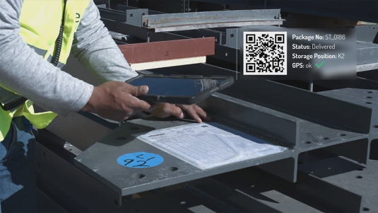 Bauarbeiter übernimmt Warenlieferung auf der Baustelle, indem er den QR-Code auf der Packliste per Material Management App scannt.