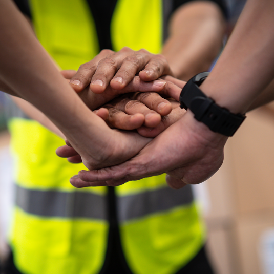 Material Tracking Software should consolidate forces. A picture shows many hands of workers stacked on top of each other.